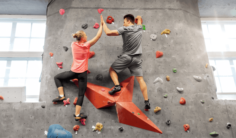 two people scaling a bouldering wall in a climbing gym two people scaling a bouldering wall in a climbing gym