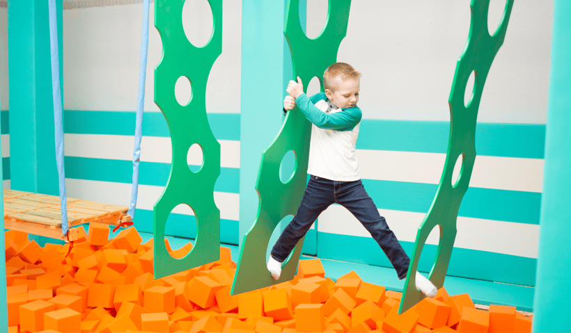 A young boy moving through an obstacle course at a ninja warrior gym