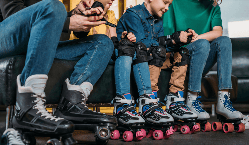 A family putting on roller skates, knee pads and wrist guards A family putting on roller skates, knee pads and wrist guards