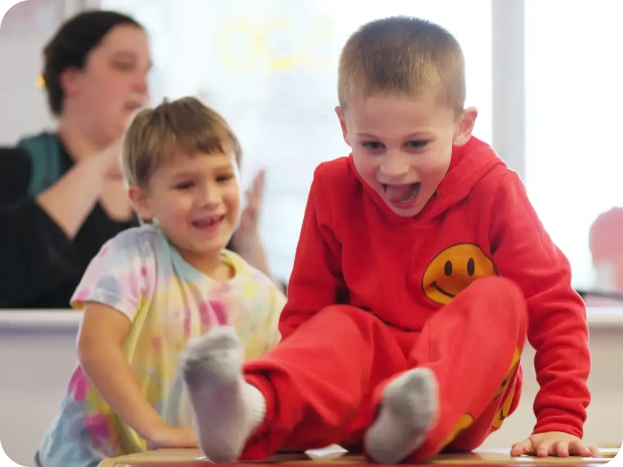 Staff member playing on the floor with two young children at We Rock The Spectrum Kid's Gym